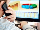 Man on a phone analyzing financial data and charts on computer