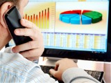 Man on a phone analyzing financial data and charts on computer Use Google Analytics to Set Your Inbound Marketing Goals for 2012